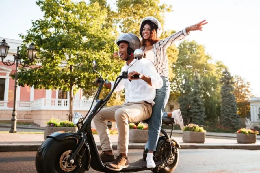 Duas pessoas andando de scooter elétrica, após escolherem um modelo.